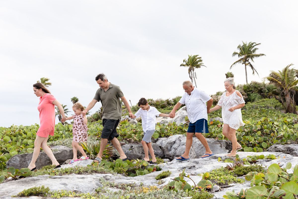 Family navigates walking on beach rocks holding hands