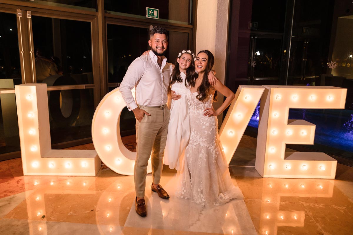 Newlyweds pose with their beloved daughter by the Love Sign