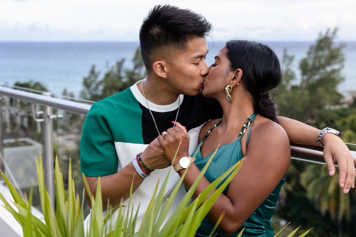 Newly engaged couple kiss on the balcony of Mvngata overlooking the ocean