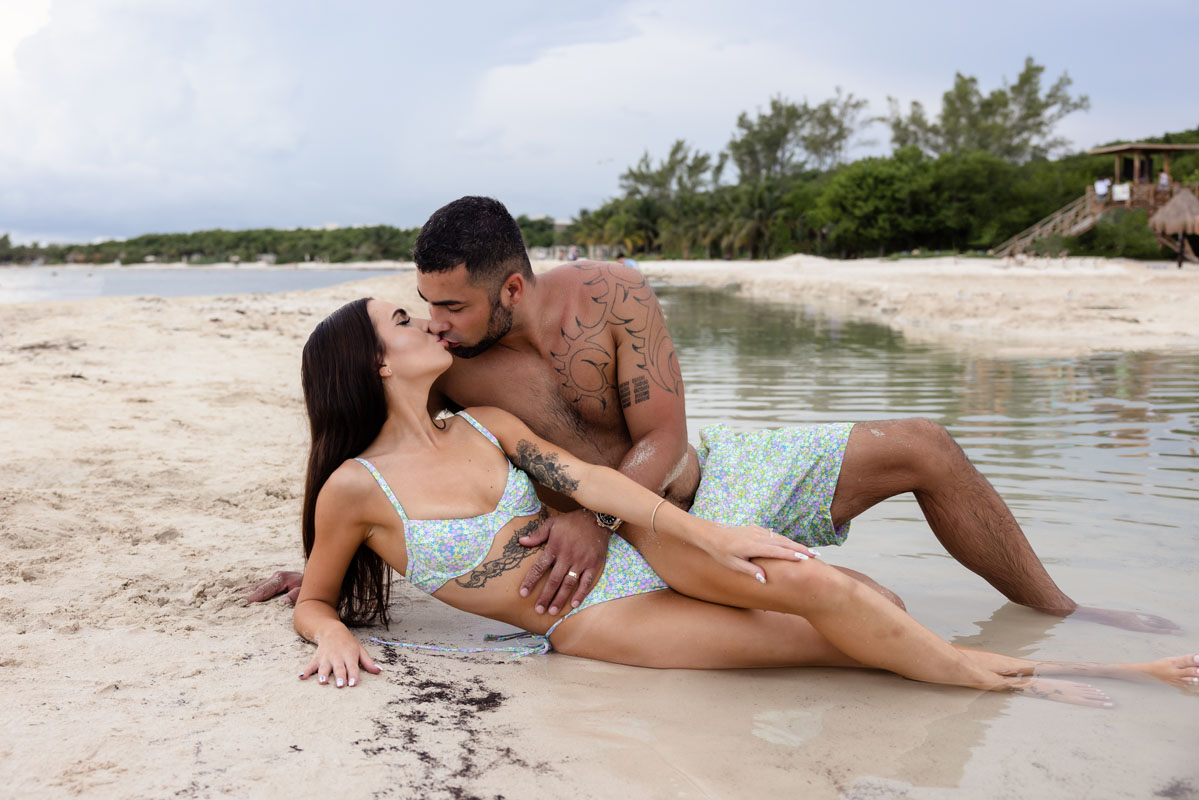 Loving couple kiss reclining in beach shallows