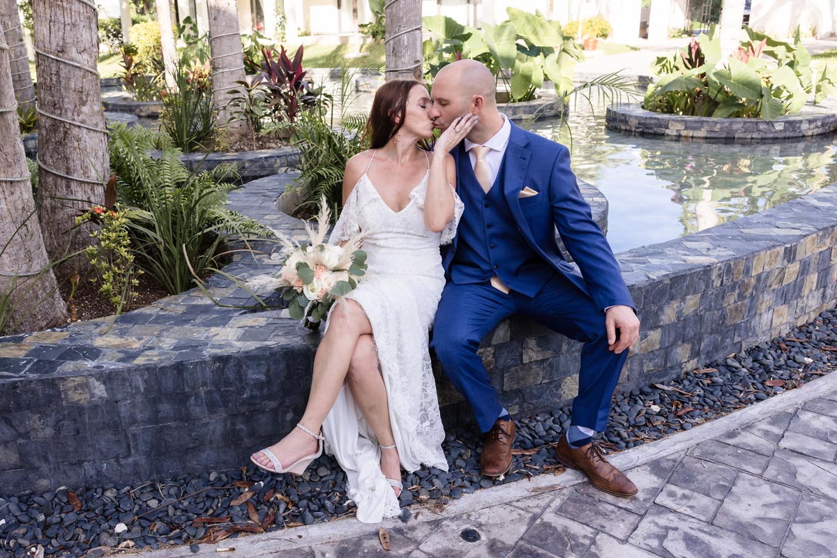 Newlyweds kiss sitting on pool wall