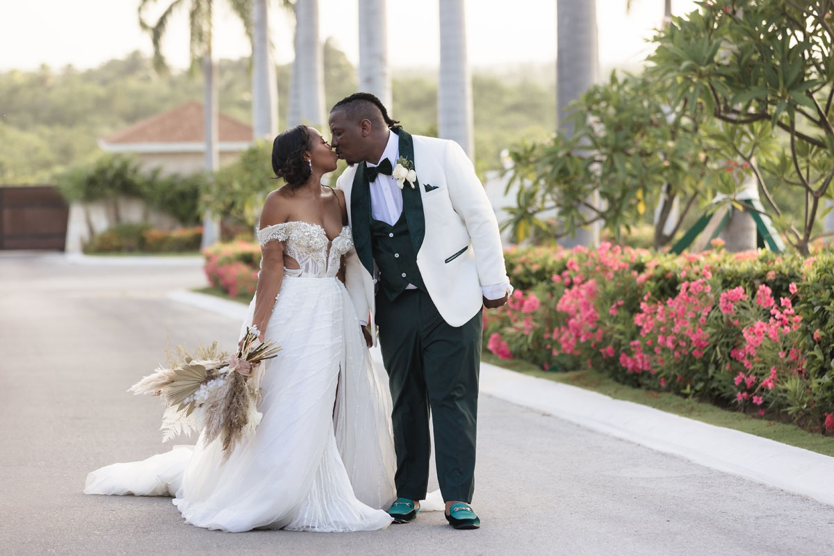 Newlyweds kiss strolling along winding driveway
