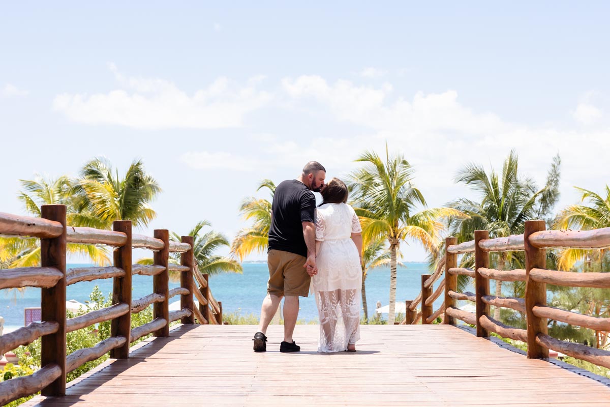 Couple kiss on Planet Hollywood bridge by ocean and palm trees