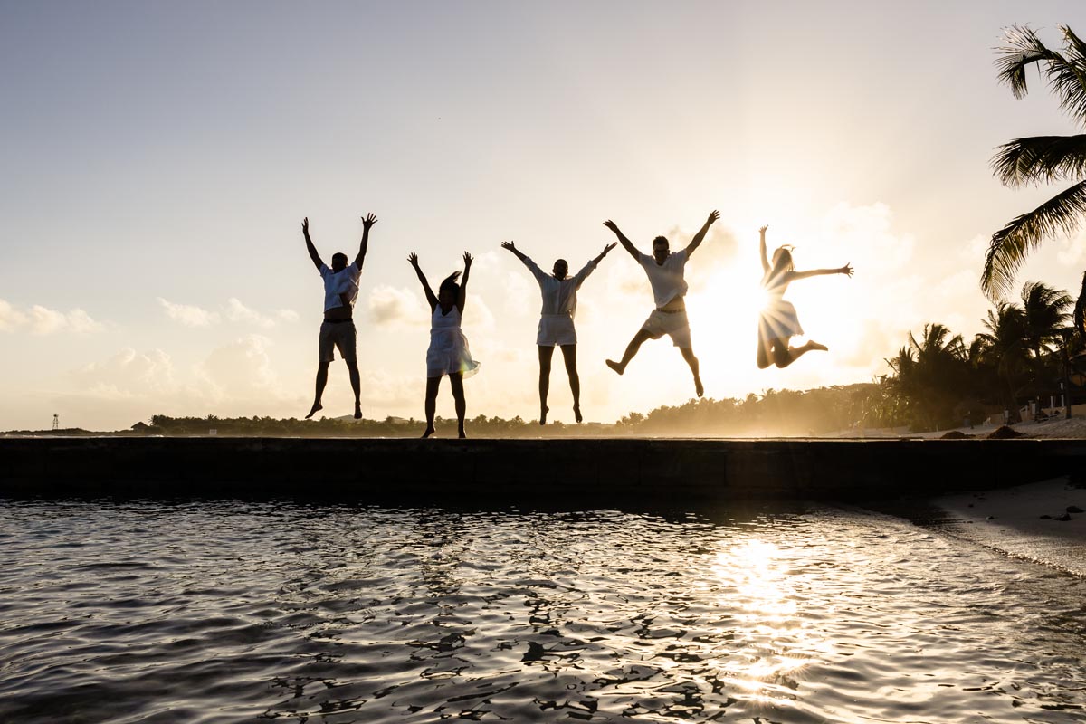 Family jumps for joy silhouetted in sunset glow