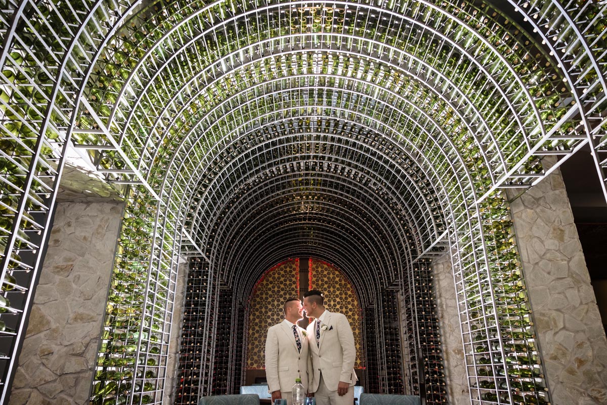 Wedding couple embrace under Royalton's wine bottle arch
