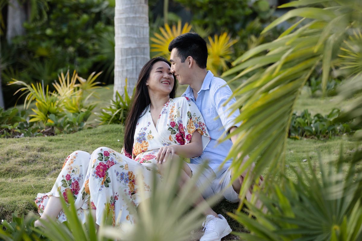 Newly engaged couple embraces sitting in tropical garden