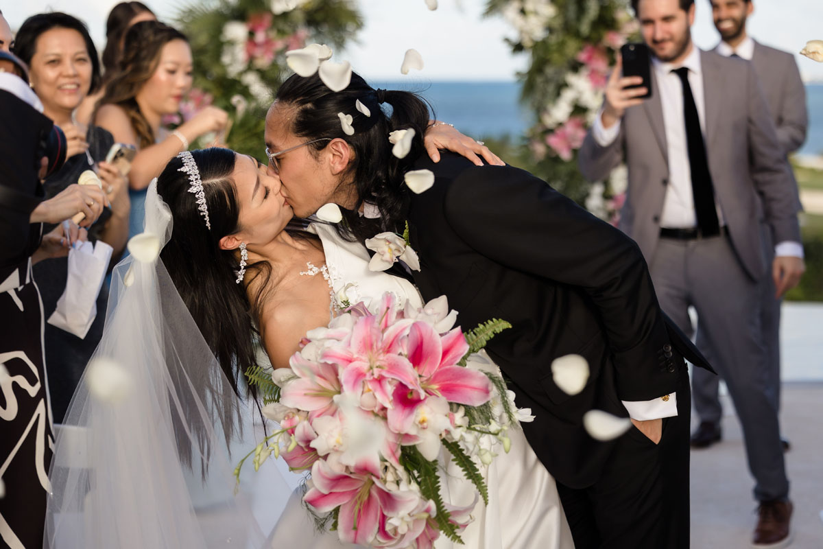 Newlyweds dip in a kiss under shower of petals
