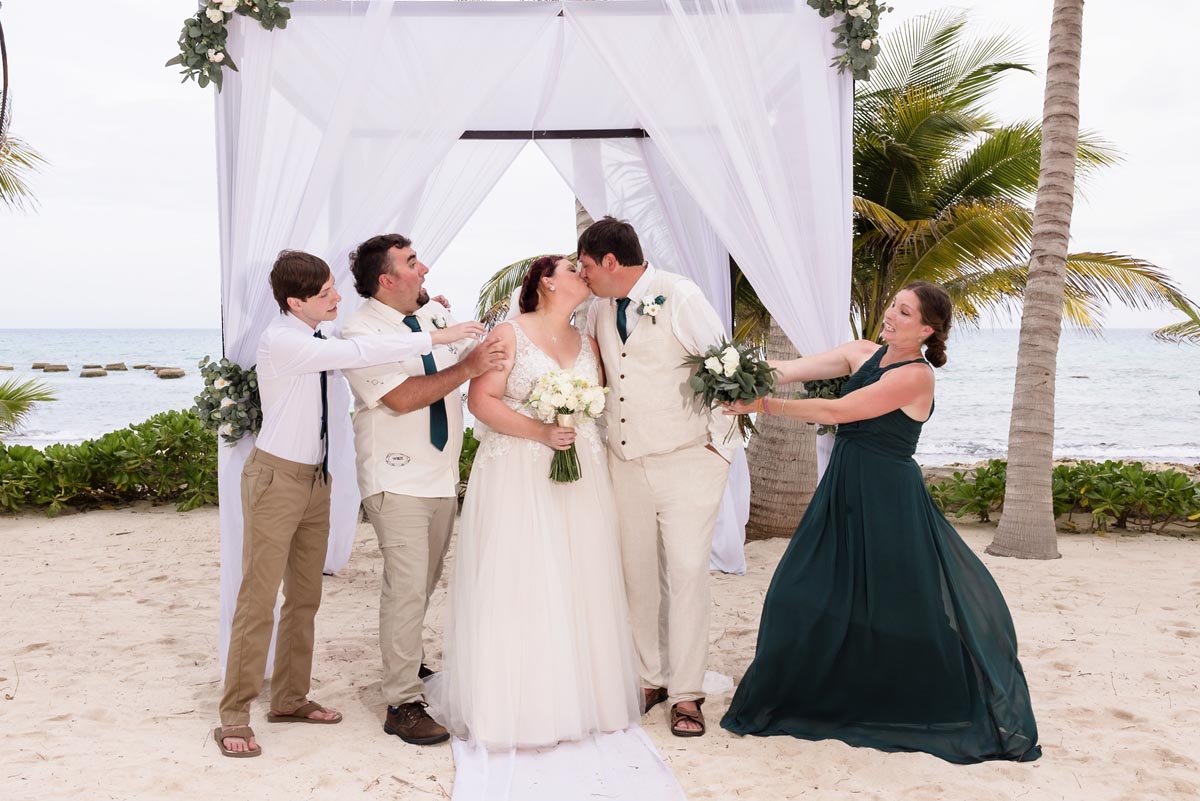 Attendants tug at kissing newlyweds to pull them apart