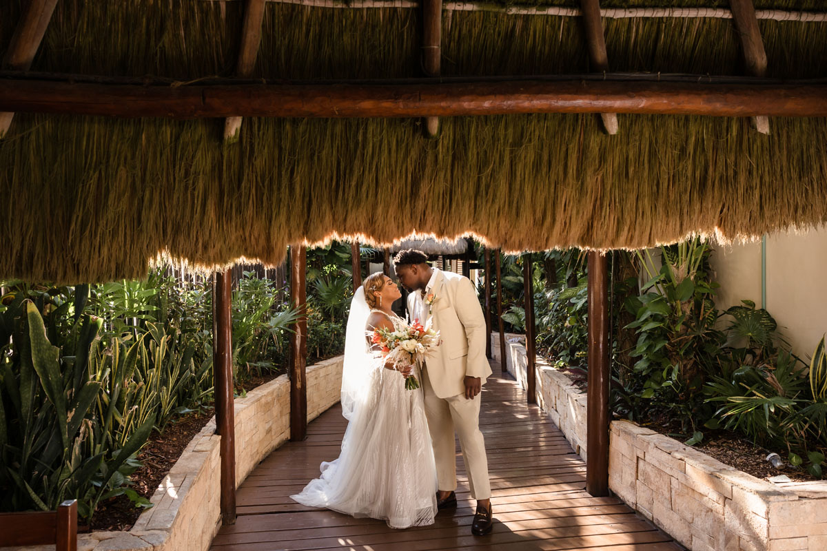 Newlyweds kiss on palapa walkway