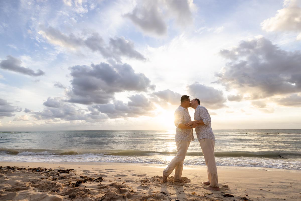 Couple embraces on sunlit beach in a kiss