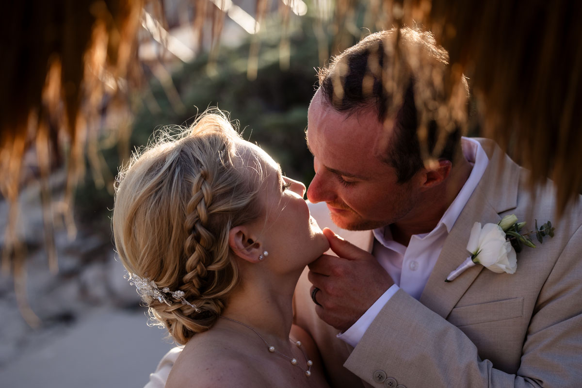 Newlyweds kiss in golden light of setting sun