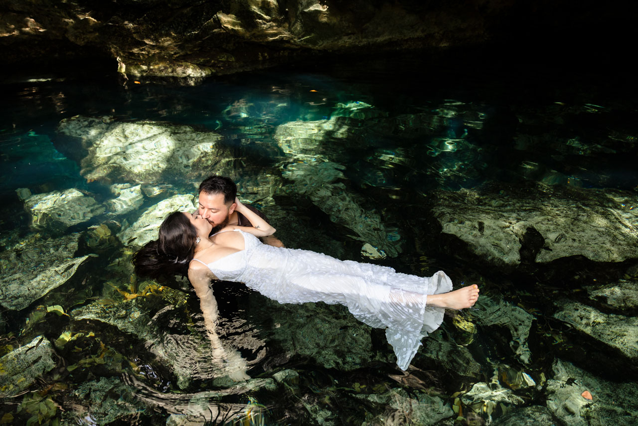 Couple kisses while floating in the cenote waters