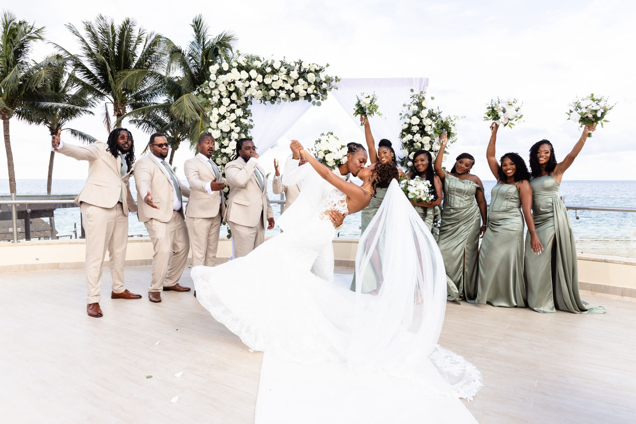 Attendants cheer newlyweds dipping in a kiss