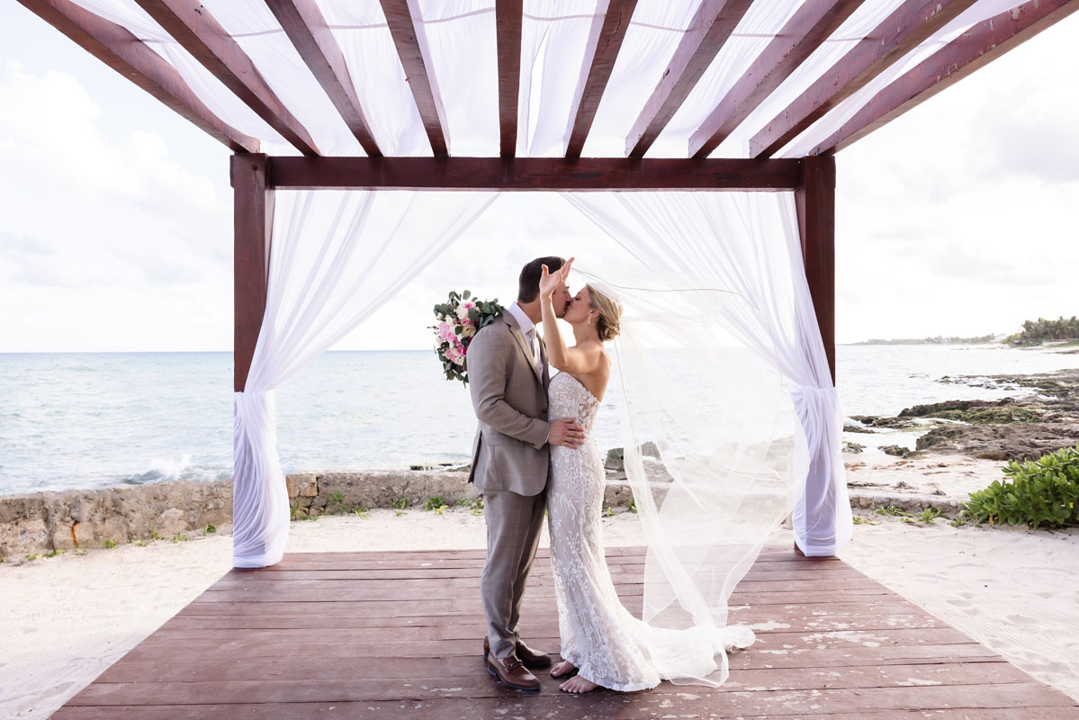 Newlyweds kiss under beachfront pagoda