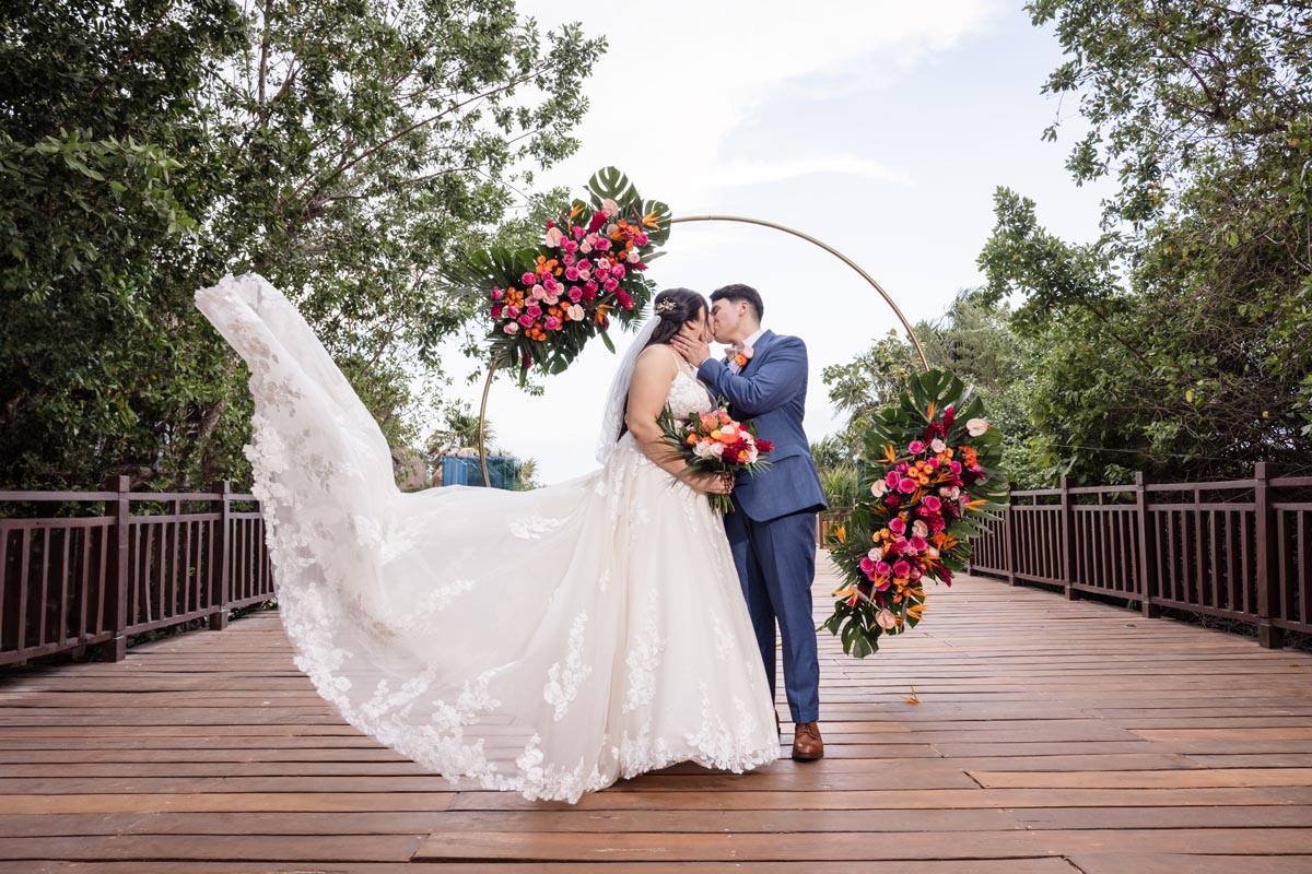 Newlyweds kiss after ceremony with brides gown floating on the breeze
