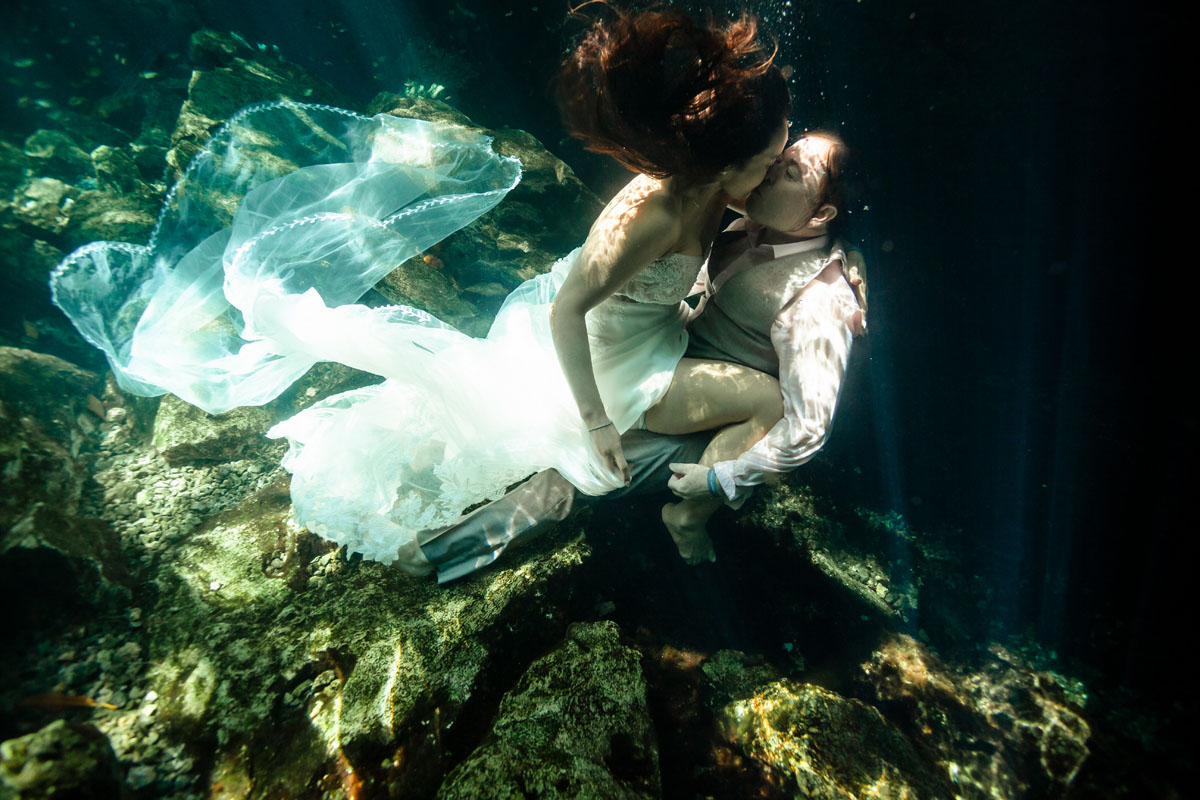 Annie + Mark kiss in the crystal clear waters of an ancient sacred cenote