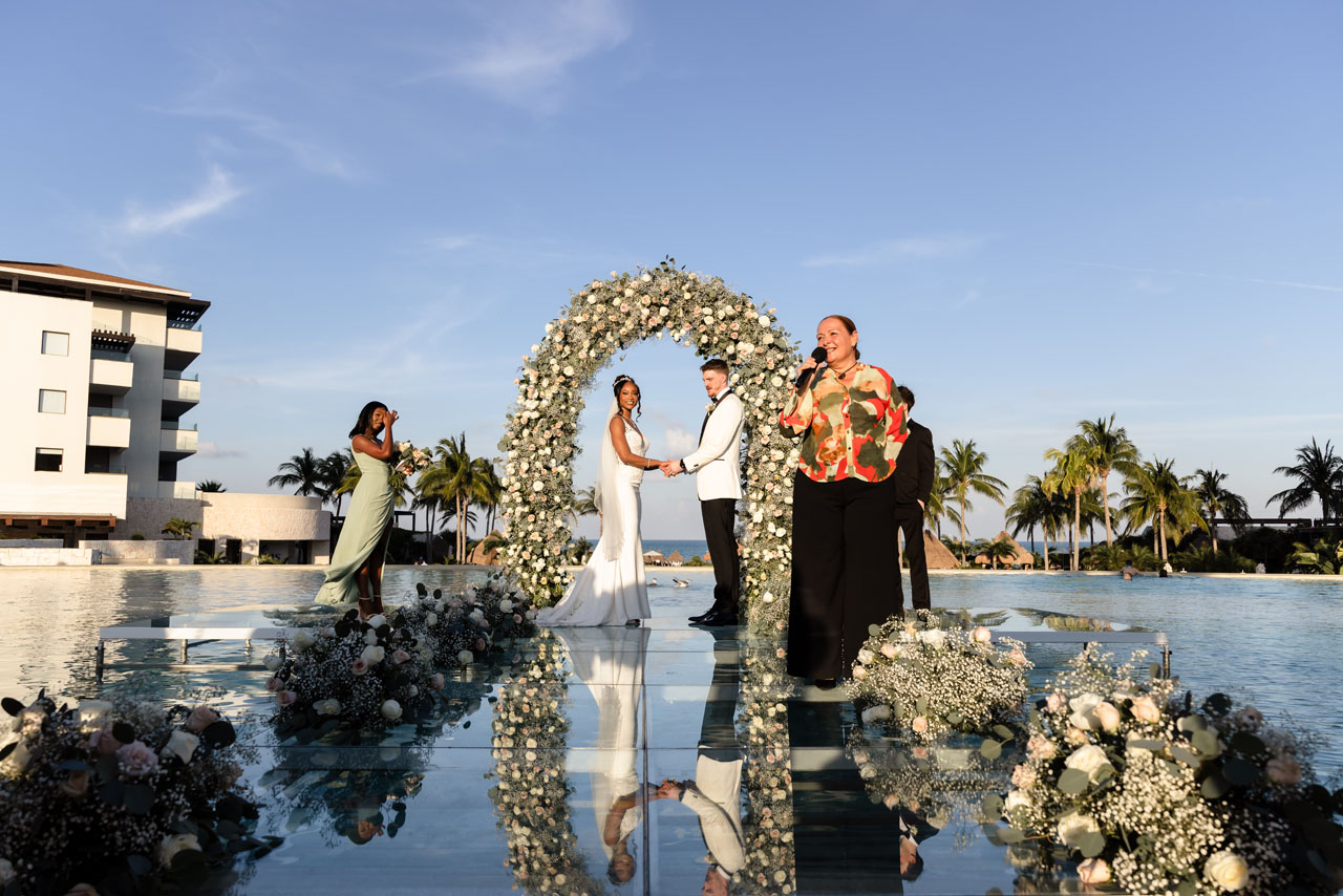 Wedding couple on glass platform overlooking pool and ocean