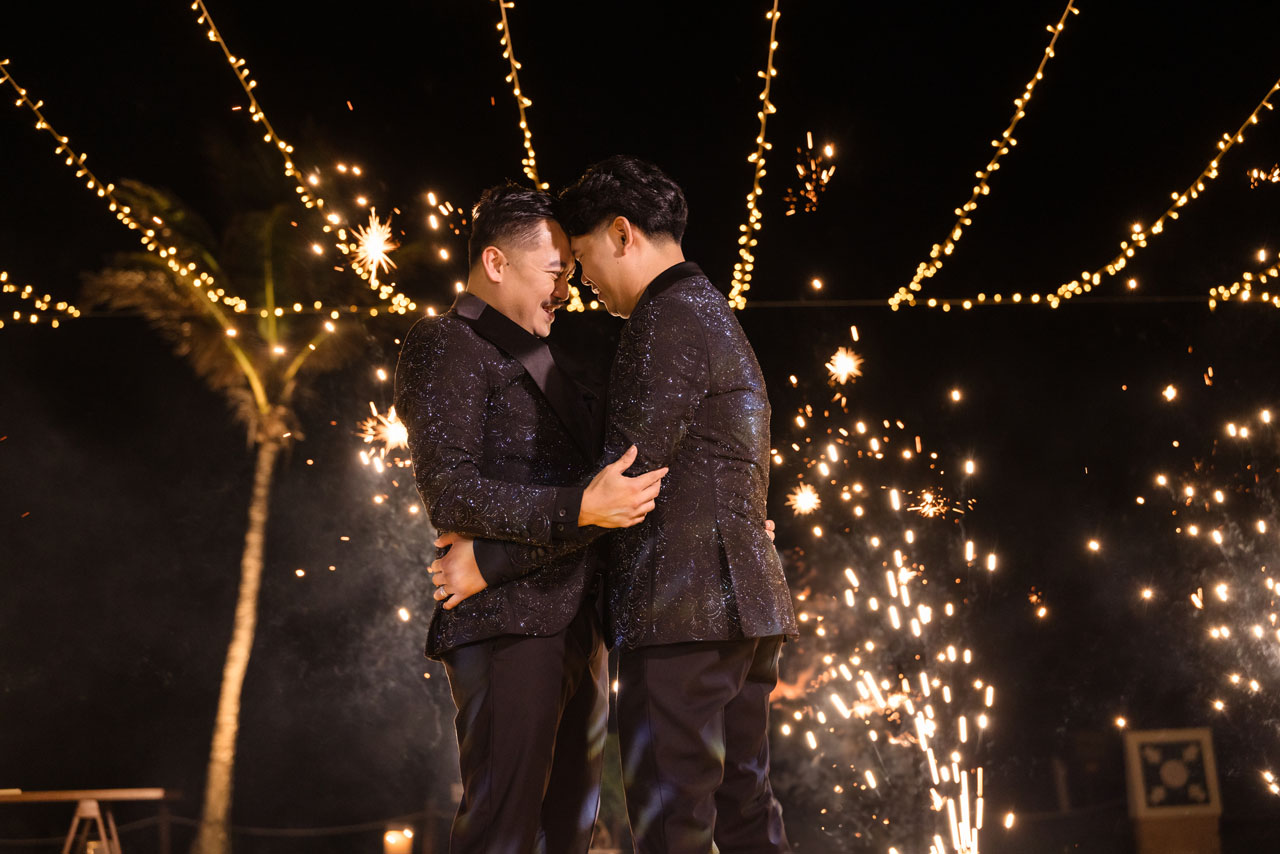 Newlyweds embrace in first dance, framed by spouting fireworks