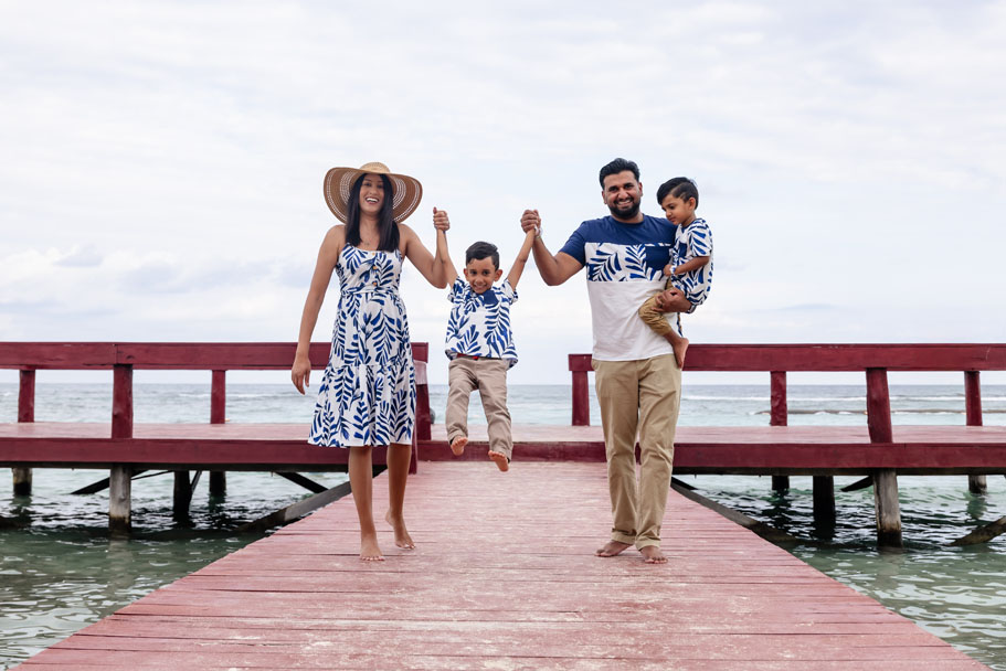 Happy family walks pier while swinging older brother