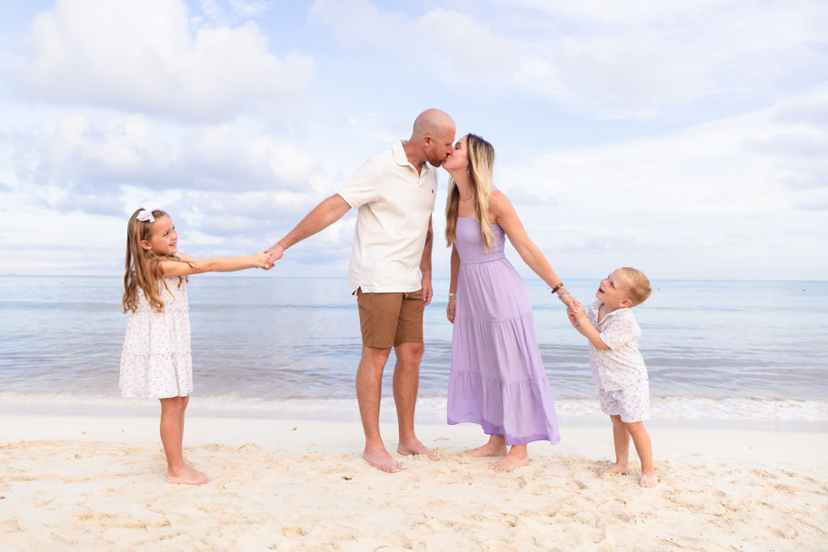 Kids pulling their kissing parents apart on the beach